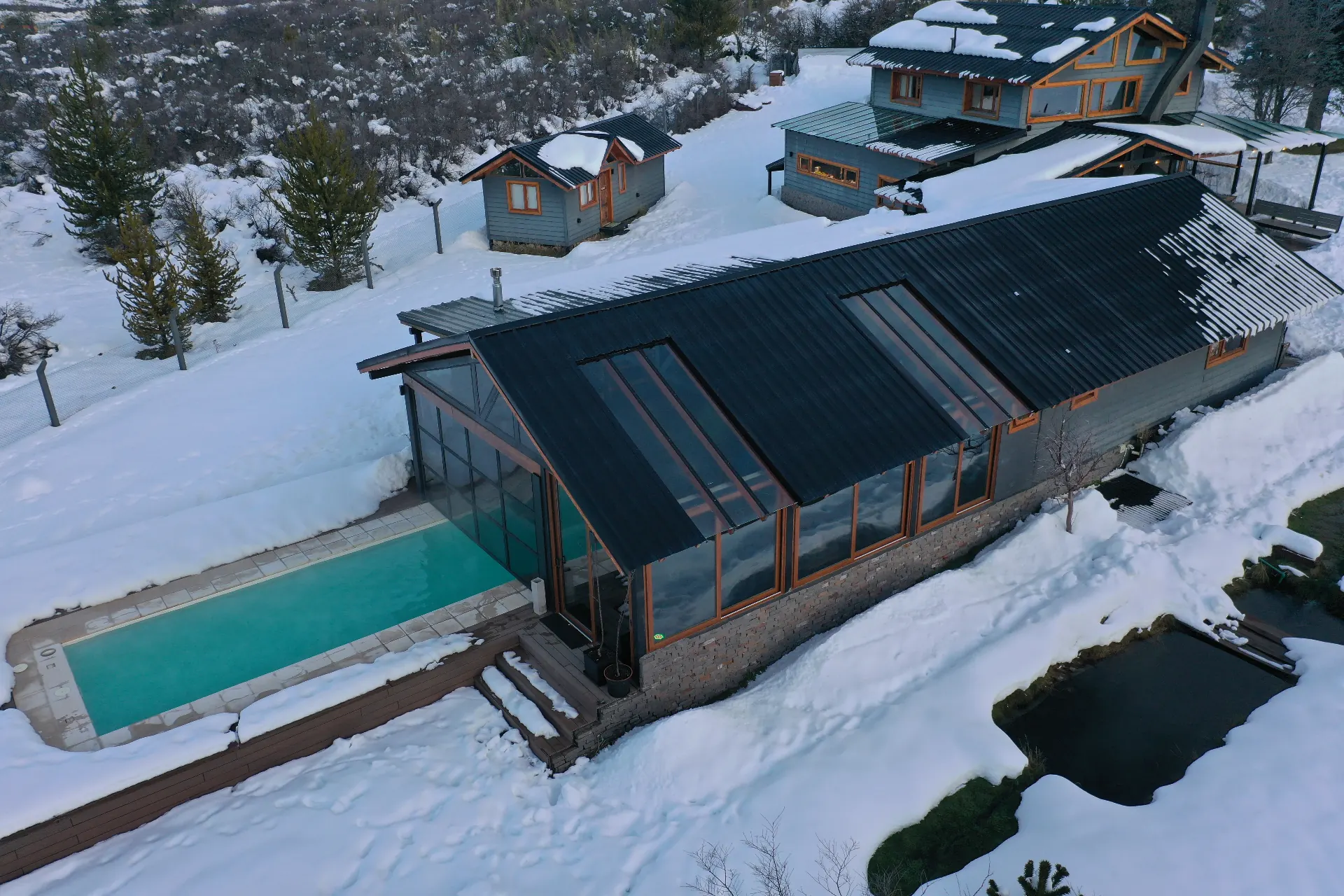 Patagonia cabin with heated pool and snow-covered roof at sunset near Bariloche