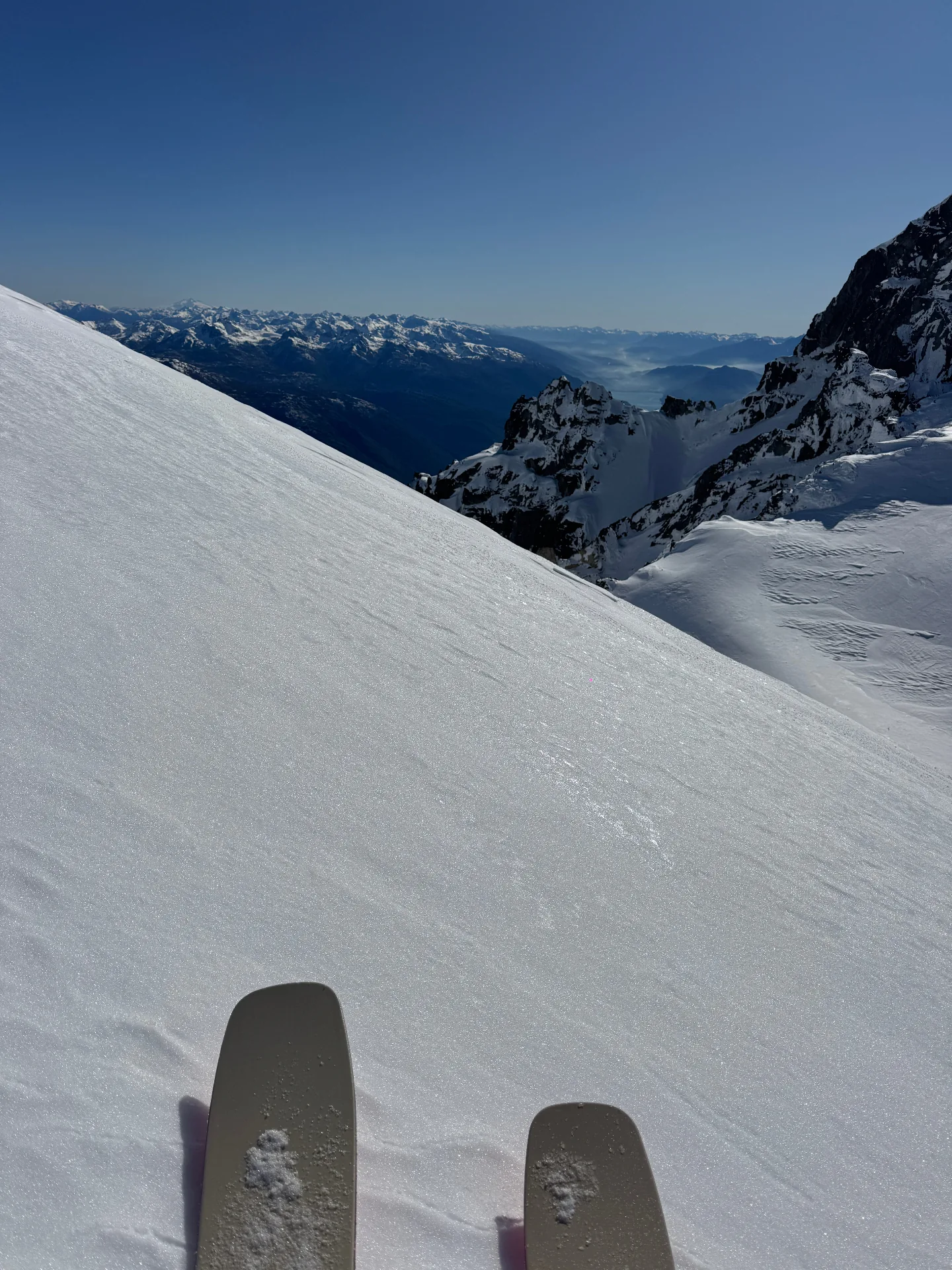 Ski tourer's first-person view from a Bariloche summit above Cerro Catedral with Lake Nahuel Huapi in the distance, Refugio Frey ski touring