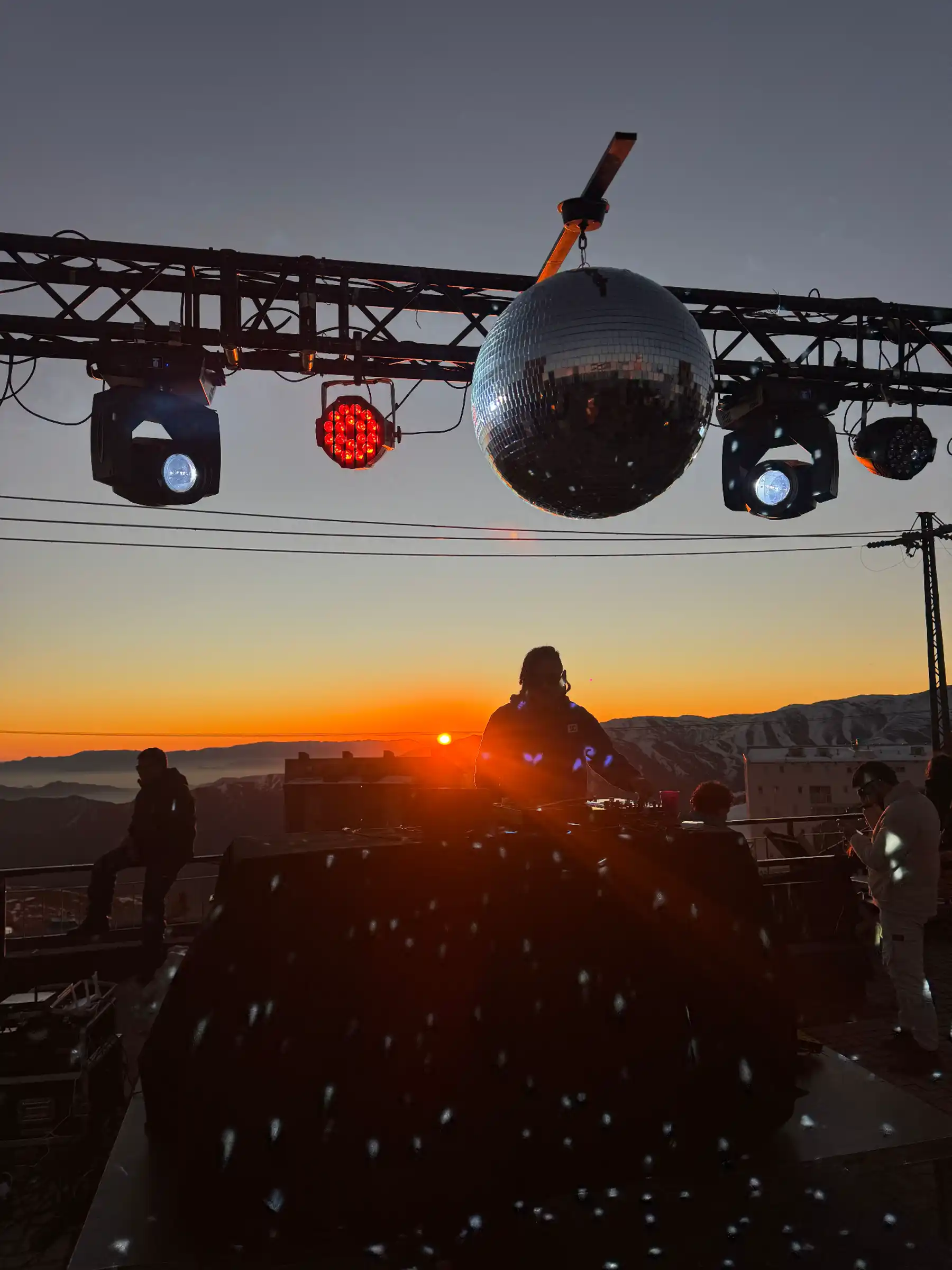 Summit après-ski DJ set at sunset with mountain ridgeline behind El Colorado