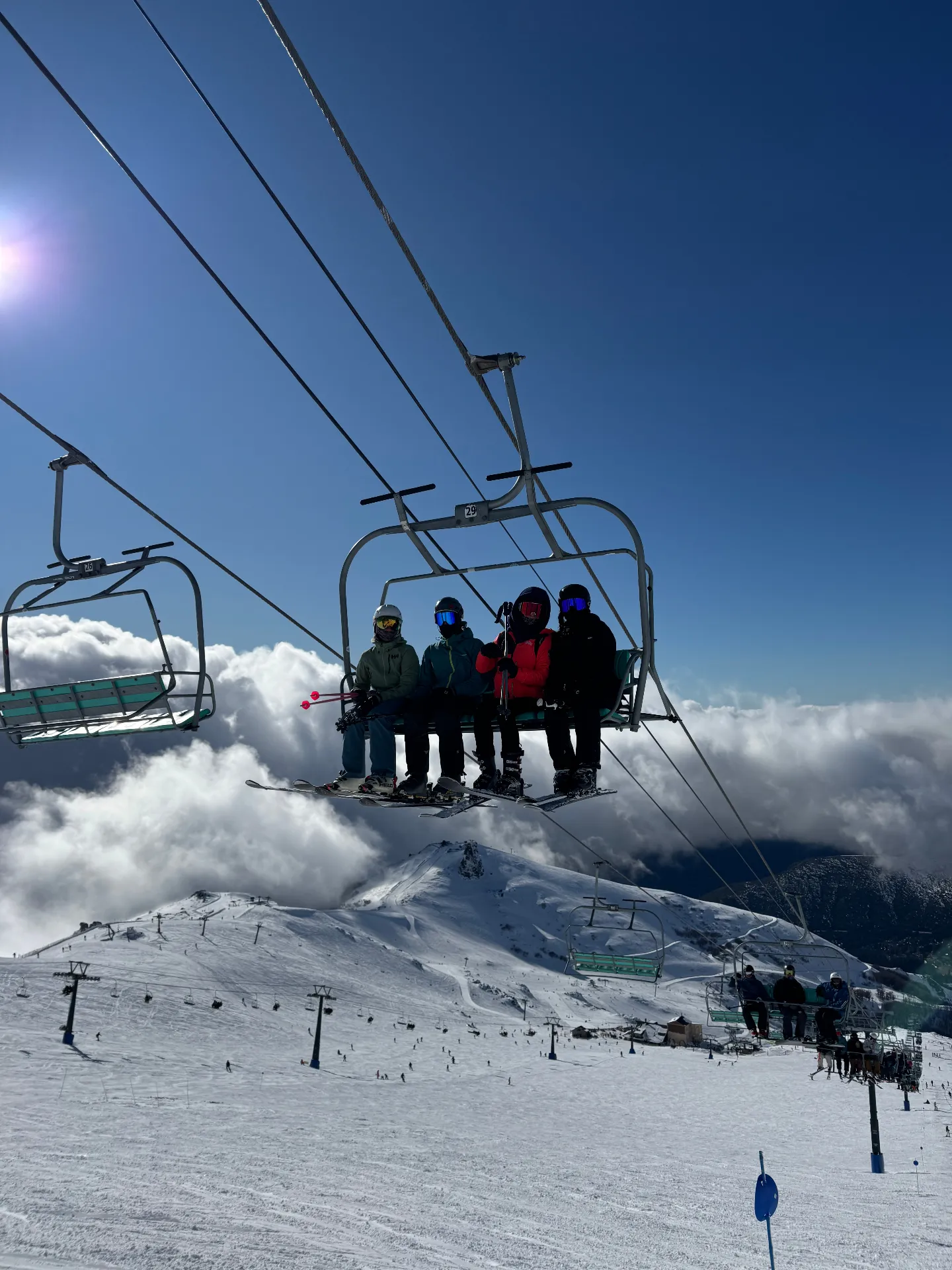 Skiers on a chairlift above the clouds at Cerro Catedral, Bariloche