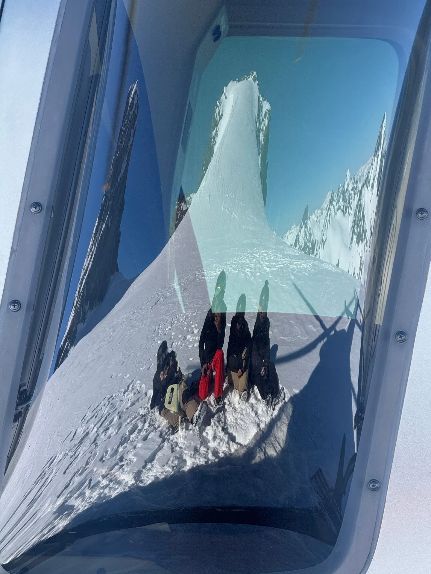 View through a helicopter cabin window of a high Andes summit ridge