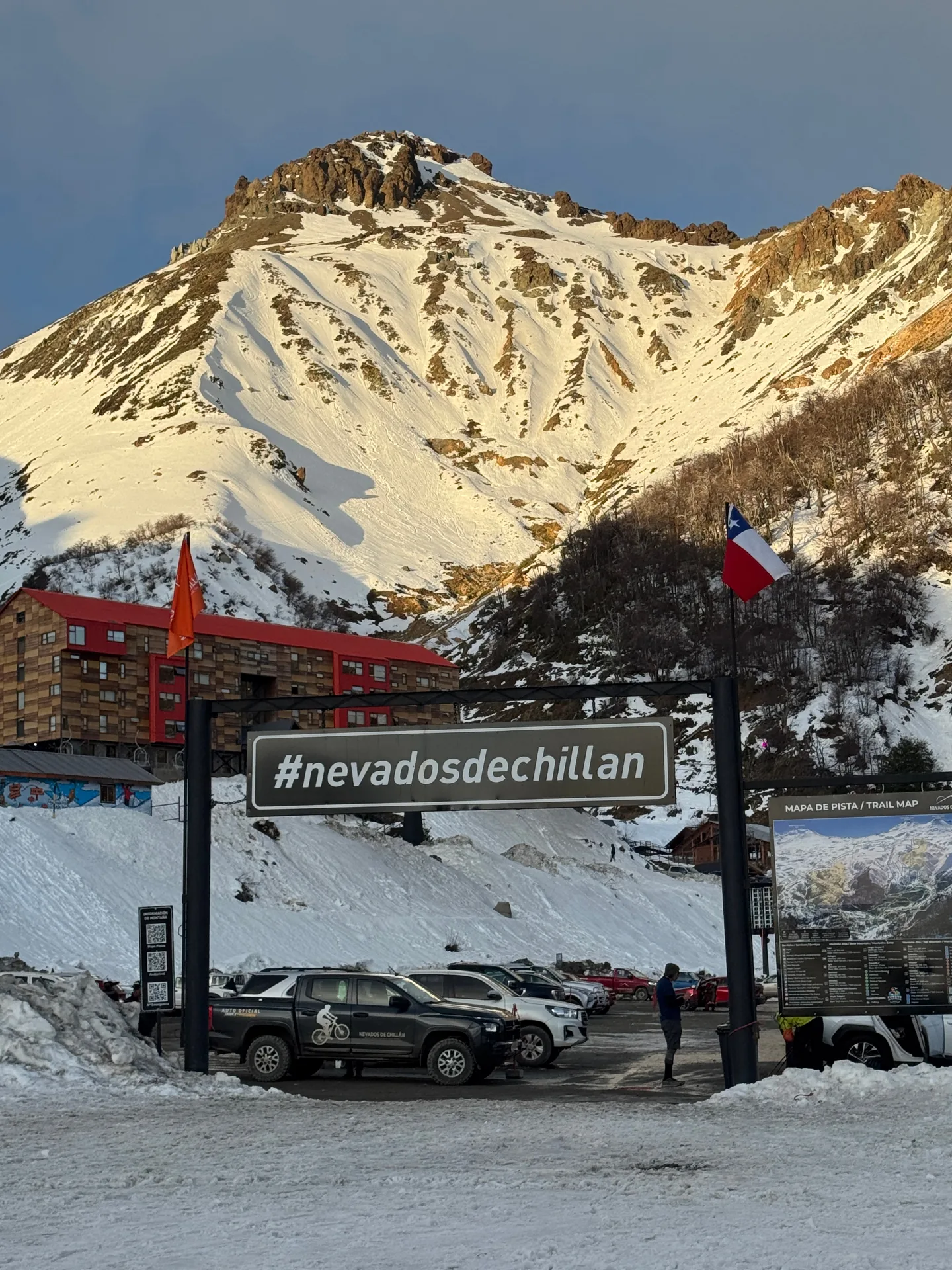 Entrance to Nevados de Chillán ski resort in central Chile with the volcano summit lit by sunset above the base lodge