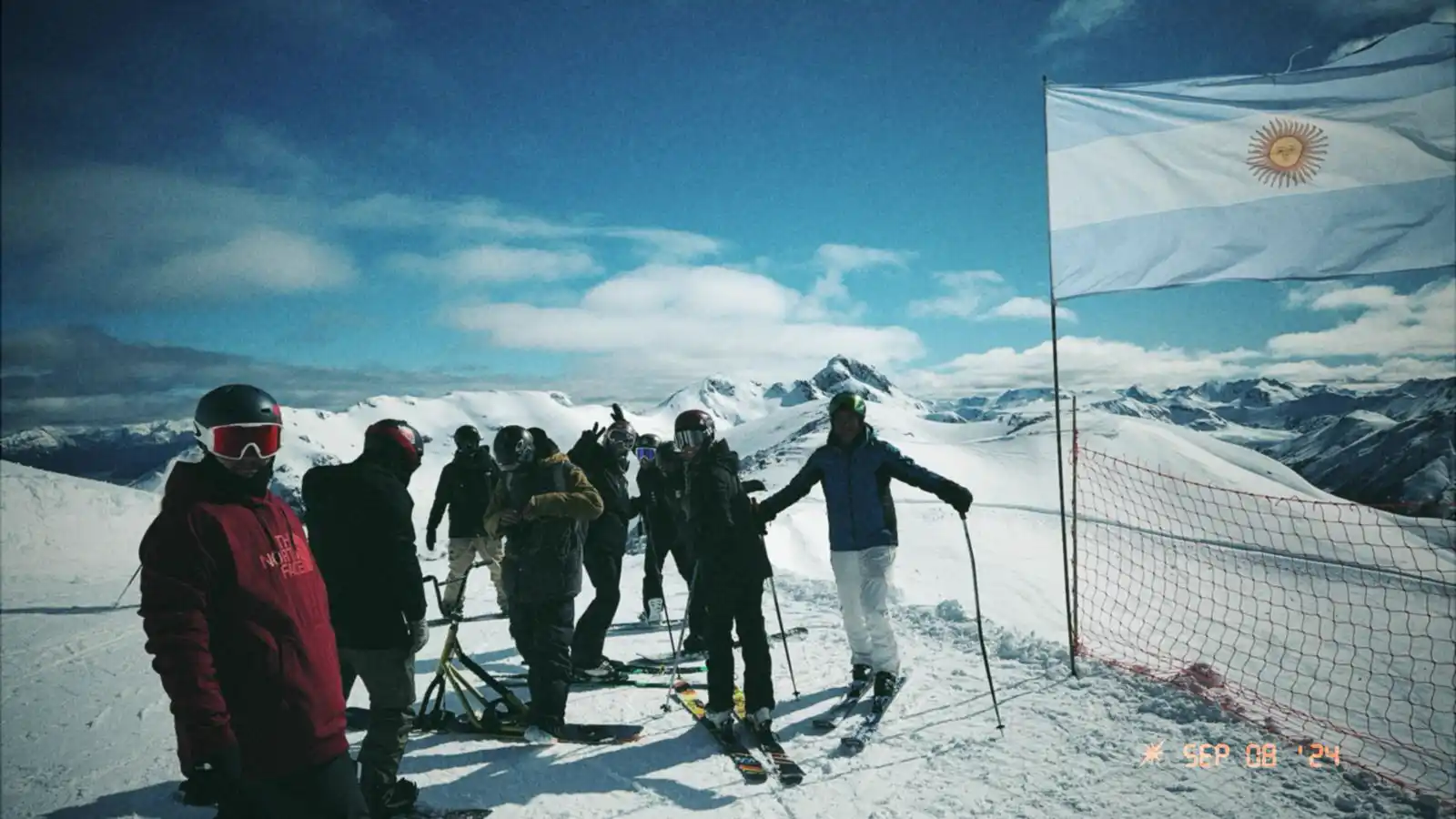Group of skiers and snowboarders at the summit of Cerro Bayo with the Argentine flag